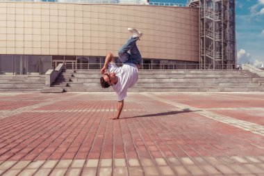 Modern man dancer, stand on one arm, dancing breakdance, summer in city, free space text, hip-hop dancer. Youth lifestyle, active, trend fitness sport, positive motivation.