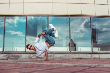 Strong man acrobat dancer, dancing breakdance, summer city, free space for text, hip hop dancer. Youth lifestyle, active, trend modern, fitness sport, positive motivation.