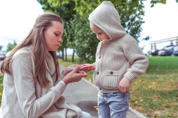 Woman mom holds a child in her arms, little boy son, autumn outdoors, warm casual clothes, grass tree background. Look at insect bug in hands. Emotions of love care and support. — Stok fotoğraf