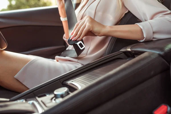 Close-up, uma menina de terno rosa, aperta o cinto de segurança no compartimento do passageiro. Activação de airbags. No verão na cidade . — Fotografia de Stock
