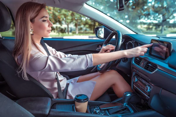 Business woman car, summer autumn day city, finger selects on touch screen, application on off, search navigation, music switching. Casual makeup pink formal suit. Automatic gearbox parking lot. — Stock Photo, Image