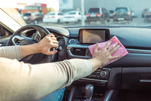 Primo piano, pulisce a mano polvere e sporcizia nell'abitacolo dell'auto parcheggiata presso il centro commerciale. In estate in città. Tovagliolo rosa, pulizia te all'interno della macchina da batteri nocivi e nel condotto . — Foto Stock