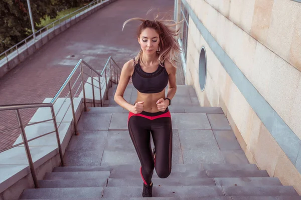 Menina bonita jogging manhã cidade correndo salto, fundo escadaria, espaço livre para texto cópia. Vista frontal. Treinamento de fitness estilo de vida ativo. Mulher atlética bronzeada. Sportswear Leggings Top . — Fotografia de Stock