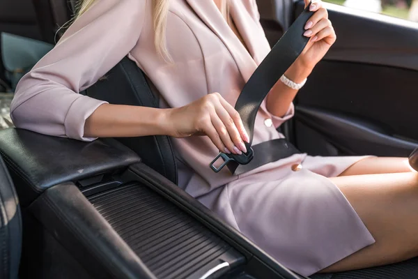 Közelkép, rózsaszín öltönyös lány, becsatolja a biztonsági övét az utastérben. Légzsákok aktiválása. Nyáron a városban.. — Stock Fotó