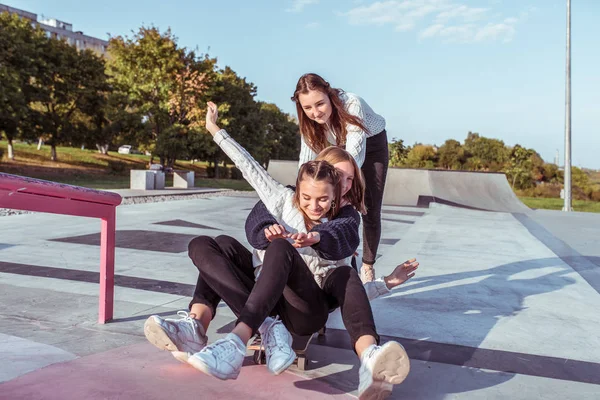3 meninas adolescentes alunas 13-15 anos, dia de outono, cidade de verão, skate, sorrisos felizes, alegrar-se rir. Diversão prazer melhores namoradas. Descanse depois da escola. Camisola jeans desgaste casual . — Fotografia de Stock