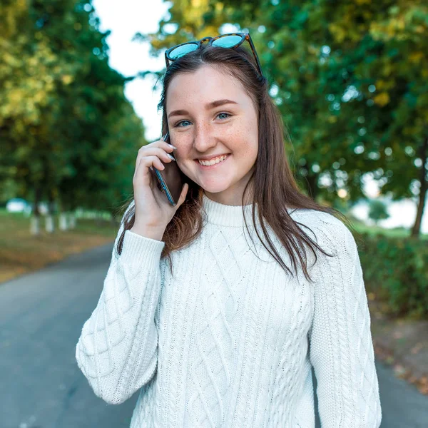 Happy joyful girl teenager 12-15 years old, autumn day, portrait on street, making phone call, summer park. Listens voice message. Emotions happiness fun pleasure. Call to parents, parenting.