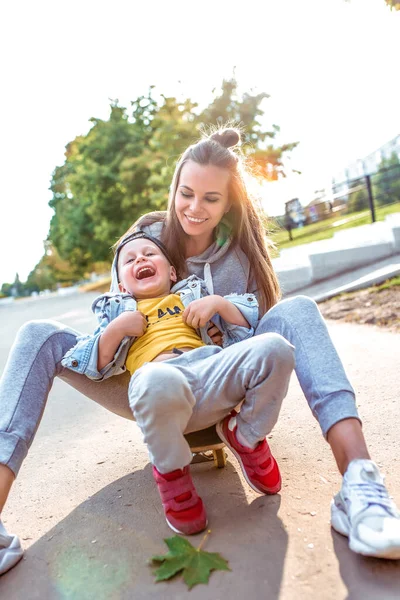 Счастливая веселая молодая семья, маленький мальчик 3-5 лет, мама женщина, весело провести лето в городском парке. Выходной отдых на спортивной площадке. Случайная одежда. Эмоции любви заботы и воспитания . — стоковое фото