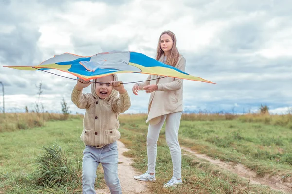 Woman mother child, little son boy 4-5 years old, autumn park, launching toy kite, playing, fun, emotions of happiness, joy and laughter of pleasure, casual warm clothes with hood. Parenting. — Stock Photo, Image