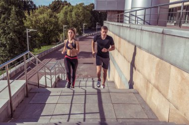 Yazın, şehirde, genç bir çift, koşuyor, zıplıyor, zıplıyor. Metin motivasyonu için boş alan. Spor Giyim Biçimli Spor Ayakkabı Tişörtü.