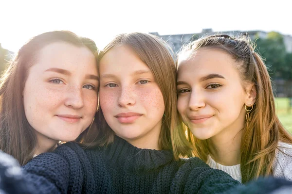Drie tienermeisjes van 12-14 jaar oud, zomer stad kijken video 's telefoon, gelukkig glimlachende mensen hebben plezier verheugen. Selfie portret close-up. Vrijetijdskleding, truien. Emoties van positieve ontspanning. — Stockfoto