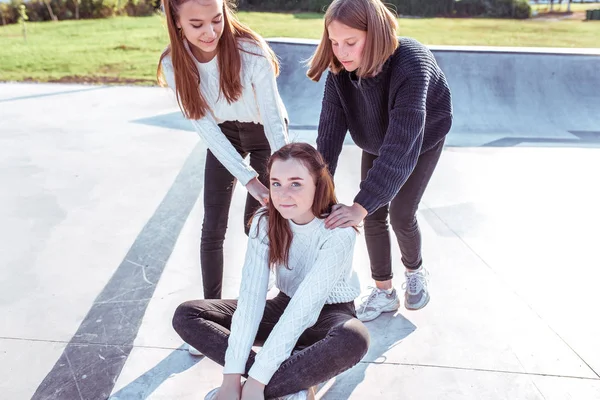 Tre ragazze adolescenti di scolarette 11-14 anni, in estate in città, cavalcano lo skateboard, sorridono felici, si divertono gioendo. Weekend libero. Vestiti casual, maglioni caldi. Emozioni positive e delizia — Foto Stock