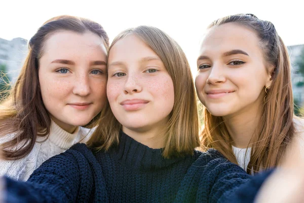 Retrato de cerca, tres niñas colegialas adolescentes, verano al aire libre. Fotografía en el teléfono, foto selfie, teléfono inteligente aplicación en línea, redes en Internet. Emociones de felicidad sonrisa, relajación diversión . — Foto de Stock