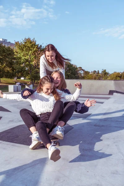 3 gadis muda gadis sekolah naik skateboard taman musim panas. Casual memakai jeans sweater. Emosi kebahagiaan, menyenangkan, relaksasi, senyum tawa, pacar terbaik, istirahat setelah kuliah — Stok Foto