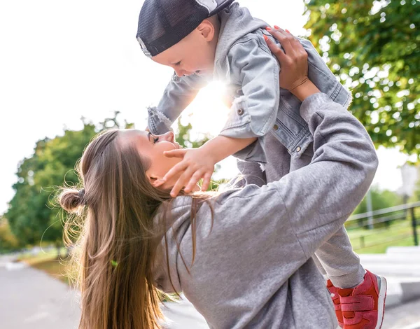 Joyful family, woman, mother raises a child, a son of a boy, have fun, play and enjoy. In summer in city. Emotions of delight of laughter of happiness, pleasure, care and love in parenting child. — Stok fotoğraf