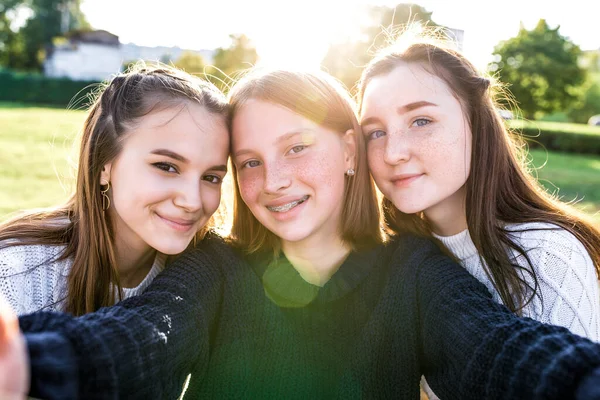 Tři školačky, selfie foto na kameře, odpočinek po školním víkendu. Léto ve městě, portréty zblízka. Emoce štěstí, zábavy, radosti, smíchu, úsměvu. Nejlepší přítelkyně. Pihy rovnátka. — Stock fotografie