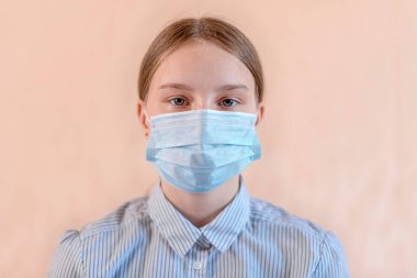 Yakından çekilmiş güzel bir portre. 12-15 yaşlarında. Yüzünü mavi bir maske takıyor. Anti-koronavirüs COVID-19 pandemik bulaşıcı hastalık salgını koruması, sağlık sigortası konsepti.