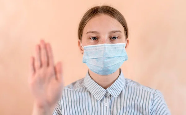 Teenager κορίτσι 12-15 ετών, σε μια ιατρική μάσκα καλύπτει το πρόσωπό της, στάση χέρι χειρονομία, προσοχή είναι επικίνδυνη, COVID-19 sars-cov-2 επιδημία πανδημία ιού επιδημία έννοια προστασίας. — Φωτογραφία Αρχείου