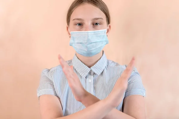 Teenager κορίτσι 12-15 ετών, σε ιατρική μάσκα καλύπτει το πρόσωπό της, σταυρόλεξο χέρι χειρονομία, διακοπή διέλευσης κλειστό, προσοχή επικίνδυνη, COVID-19 sars-cov-2 επιδημία πανδημία ιού επιδημία έννοια προστασίας. — Φωτογραφία Αρχείου