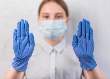 12-15 yaşlarında genç bir kız. Koruyucu tıbbi maske takıyor. Yüzü, lastik eldivenleri, el hareketlerini durdurup dikkatle karantinaya alınmış. Grip enfeksiyonu hastalık ve salgındır. Beyaz arkaplan.