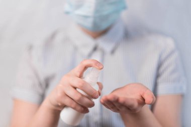 Yakın plan, çocuk elleri avucunuzun içine antiseptik, dezenfeksiyon emniyeti, gribin önlenmesi ve salgın hastalıklar ve enfeksiyondan korunmak için. Beyaz arka planda tıbbi maskeyle.
