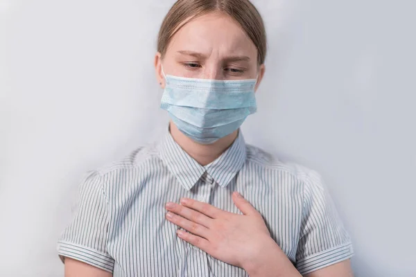 Gadis remaja berusia 12-15 tahun, dengan topeng pelindung batuk sakit tenggorokan, kesehatan yang buruk, gejala buruk, penyakit dan komplikasi, rumah sakit karantina diri di ruang medis. Stok Foto