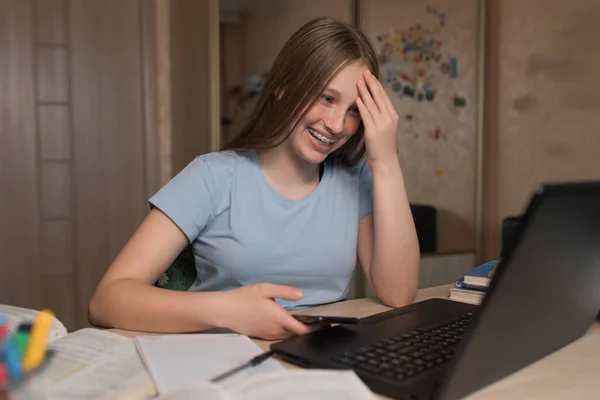 Счастливая девочка-подросток смеется, смотрит смешные видео в Интернете на ноутбуке, домашнее задание в Интернете, на ноутбуке. Дистанционное обучение и тренировочный карантин, остаться дома. Счастья, радости и веселья . — стоковое фото