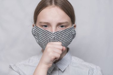Yakın plan, tıbbi maskeli genç kız öksürüyor ve hapşırıyor, virüs ve hastalık, kameraya bakıyor. Beyaz arka plan. Kendimi kötü hissediyorum. Coronovirüs salgını sırasında evde kal, covid 19..