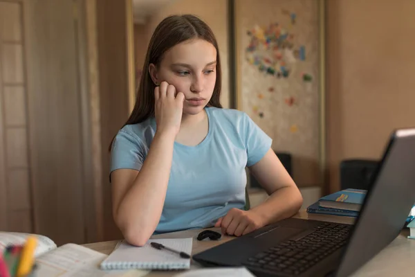 Triste y cansado, adolescente de 12-14 años, viendo videos en casa, lecciones de portátiles. Educación electrónica a distancia Internet y videocomunicaciones. Ver una película y tutoriales video tutoriales . Fotos de stock