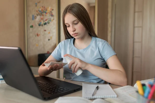 Teenager Mädchen 12-15 Jahre alt, Desinfektionsspray antiseptisch, Reinigungstuch, zu Hause Laptop-Unterricht. E-Education und Fernstudium Internet und Videokommunikation. Zusammenfassungen eines Notizbuchs. — Stockfoto