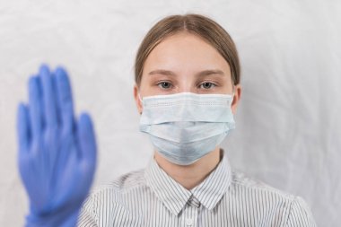 10-14 yaşlarındaki genç kız, tıbbi maske ve eldiven takıyor, gözlere odaklanıyor, ayaklara dikkat ediyor, virüs hastalıklarına dikkat ediyor, grip ve hastalıklara dikkat ediyor, evde kalıyor, koronovirüs salgınını durduruyor.