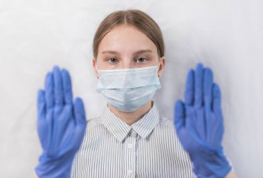 Genç kız 11-15 yaşlarında, tıbbi maske ve eldiven takmış, gözlere odaklanmış, ayaklara dikkat eden hareketler, dikkatli virüs ve hastalık, evde kal, koronovirüs kovid 19 salgınını durdur.