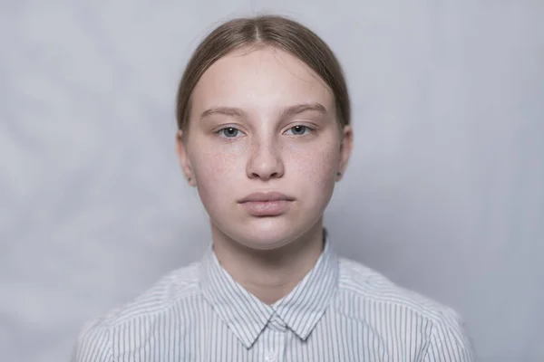 Retrato de una adolescente de 15 años, fondo uniforme blanco, camisa a rayas. Pecas en la cara. Primer plano . — Foto de Stock