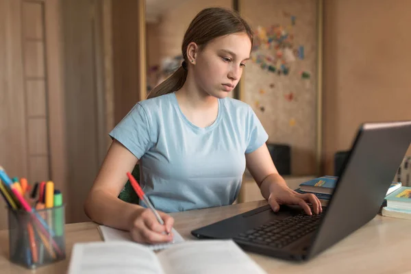 Teenagepige skriver lektioner test opgaver i notesbog, elektronisk uddannelse derhjemme, laptop, fjernbetjening videokonference på internettet. Skoleuddannelse forberedelse kollegium, kvalifikation kurser - Stock-foto