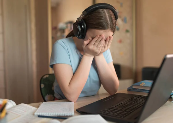 Teen girl crying upset, bad test lesson, home electronic education, laptop watching video headphones, remote video conference on Internet. School education preparation institute courses.