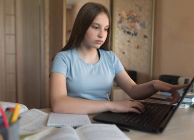 Parmakları dokunmatik ekranda seçen genç bir kız, dizüstü bilgisayarda yazılı mesaj, elektronik eğitim, internetteki uzaktan video konferansı. Okul eğitimi, hazırlık okulu, diploma kursları.