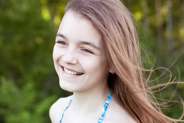 Close-up portret van een kind, mooi klein tienermeisje lachend en lachend, in de zomer in de natuur, emoties van geluk, vreugde en ontspanning. Lang haar ontwikkelt zich in de wind. — Stockfoto