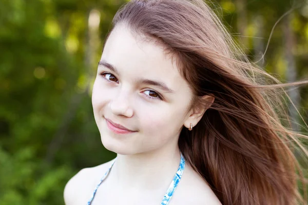 Close-up portret van kind, mooi klein tienermeisje op zoek naar bruine ogen, zomer buiten, emoties van geluk glimlach en rust. Lang haar ontwikkelt zich in de wind. — Stockfoto