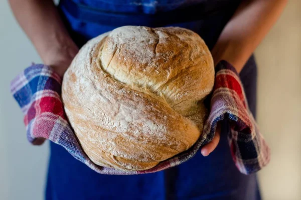 Ronde brood in de handen van een vrouw — Stockfoto