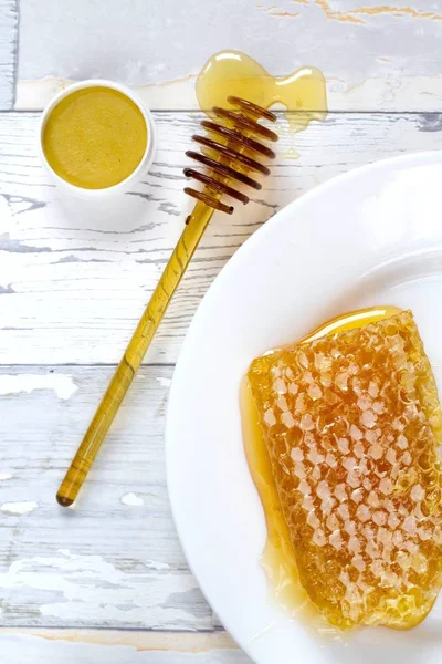 tasty organic honey in a honeycomb and honey lip balm on a wooden, vintage background