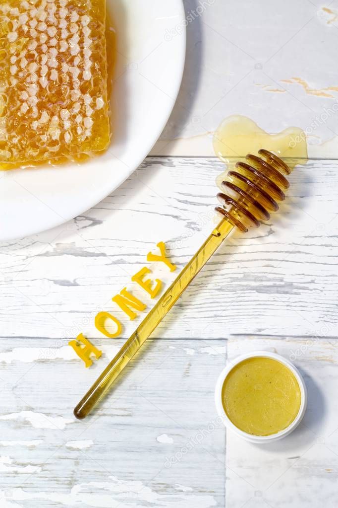 tasty organic honey in a honeycomb and honey lip balm on a wooden, vintage background