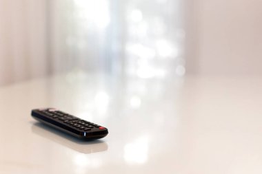 Beyaz bokeh arka planı olan beyaz bir masanın uzaktan kumandası. Fotoğraf alanı kopyala.