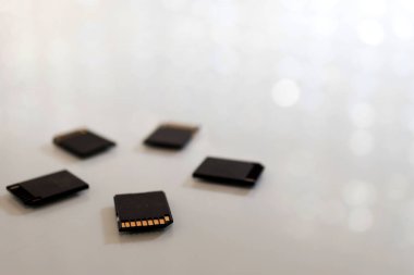 Siyah hafıza kartları beyaz bir masanın üzerine dairesel bir şekilde yerleştirilmiş. Fotoğraf: bokeh ve kopyalama alanı.