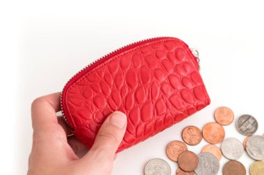 Elinde kırmızı para çantası ve beyaz arka planda bozuk paraları olan bir kadının eli..
