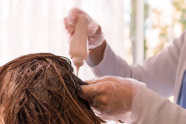 Image representing personal care at home. Hands of a person dying the hair of a woman in blond color. Indoors. Close up photo of hair. Personal care in time of coronavirus disease. No visible faces.