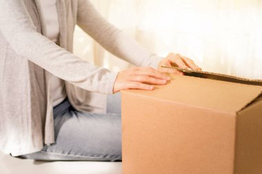 Kadın paketi açıyor. İnternetten alışveriş ile ilgili bir fotoğraf. İnternetten satın alma fikri. Boks yap. Uzayı kopyala Ticaret için. Paketi açıyorum. Görünür yüz yok.