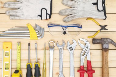 Aletler ahşap masaya kondu. Tornavida, mezura, çekiç, anahtar, eldivenler ve güvenlik camları. Teknik alet konsepti..