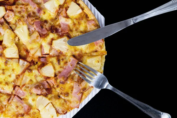 Siyah arka planda ananas ve jambonlu dilimlenmiş Hawaii pizzası. Fast food konsepti..