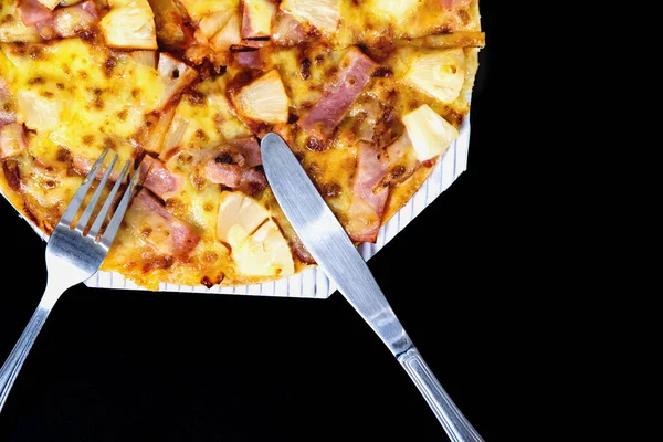 Siyah arka planda ananas ve jambonlu dilimlenmiş Hawaii pizzası. Fast food konsepti..