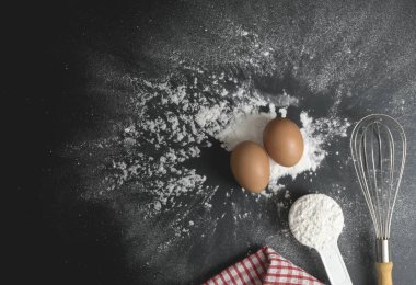 Un ve un dolu yumurtalar siyah masa üzerine serpilmiş fırın konsepti..