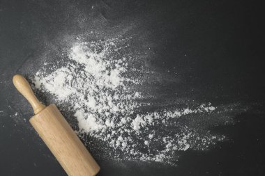 Tahta hamur silindiri, un serpiştirilmiş siyah masanın üzerinde. Pastane ev yapımı konsept.